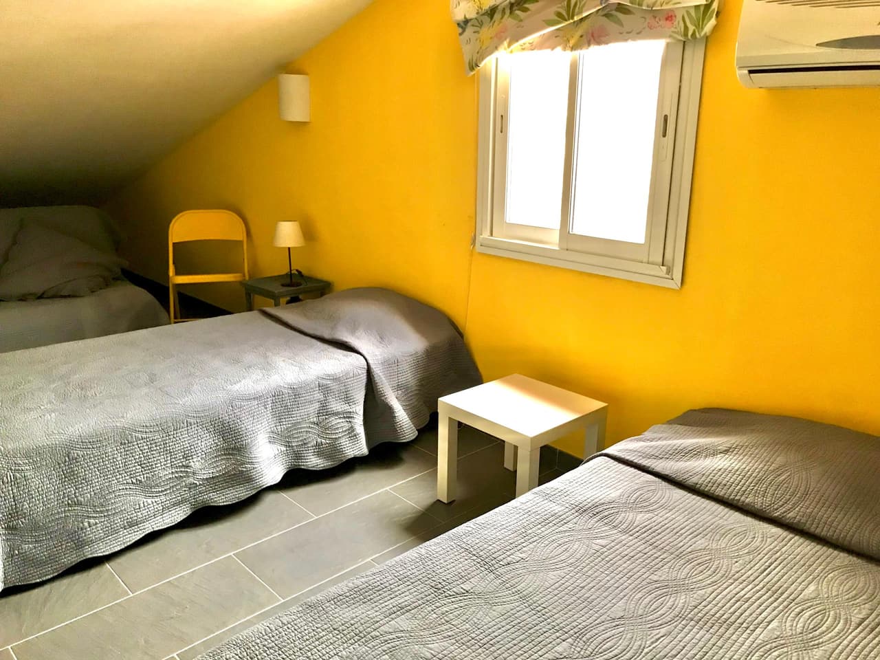 La chambre jaune sous les combles, avec ses deux lits simples et son mur jaune vif