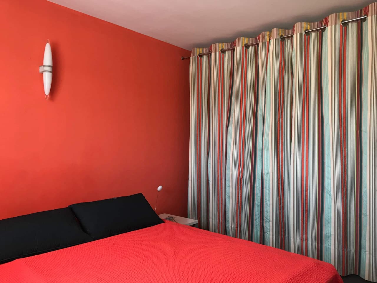 La chambre orange, au rez-de-chaussée, avec son mur vermillon et ses rideaux rayés